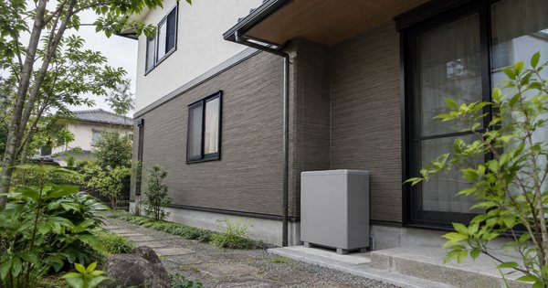 日陰の1階外壁に無地の蓄電池を設置した二階建て住宅