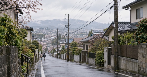 雨上がりの坂道に並ぶ住宅と電柱、電線