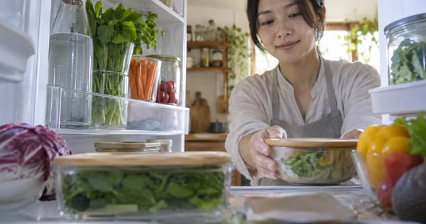 冷蔵庫の内側から、保存容器と野菜をしまう人を見た様子